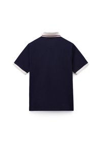 Μπ λε σκούρο πόλο μπλουζάκι με κοντά μανίκια, λευκό γιακά και κόκκινη ρίγα ως λεπτομέρεια. Ομαλή υφή με κλασική, εφαρμοστή γραμμή.