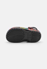 Colorful patterned Crocs with a black rubber sole, strap, and tread design. Features a vibrant multi-color upper with a smooth texture.