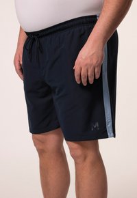 Námořnické plavky s elastickým pasem a šňůrkou. Obsahují světle modrou boční část a tištěné logo blízko lemu.