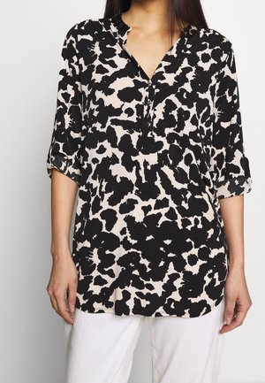 Blusa nera e beige con motivo leopardato, dotata di scollatura a V con bottoni, maniche a tre quarti e una texture di tessuto liscia.