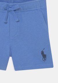 Pantalones cortos de algodón azules con cintura elástica, cordón ajustable, bolsillos laterales y un pequeño logo bordado en negro de un jinete.