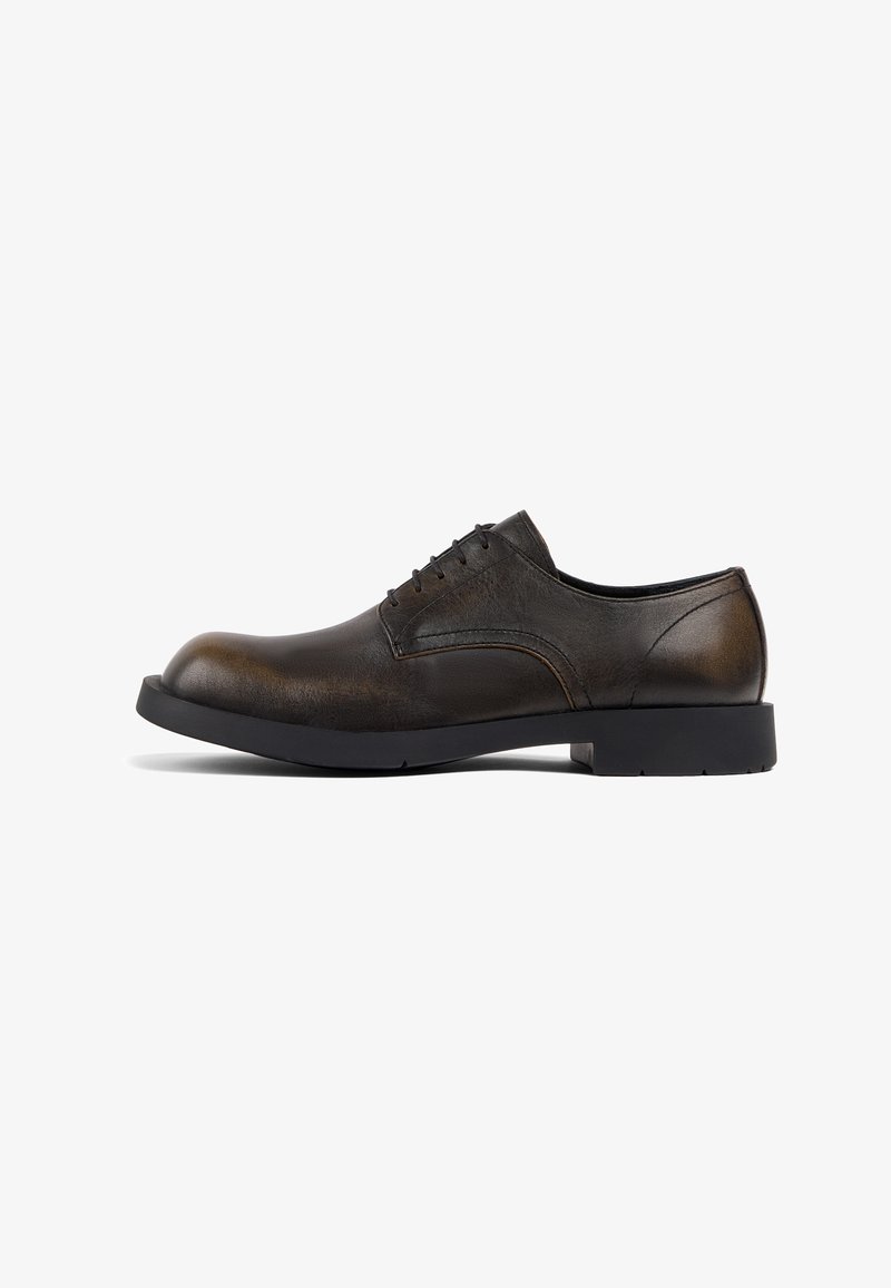Zapato de vestir de cuero marrón con punta redondeada, seis ojetes y suela de goma negra. Presenta un acabado suave con una textura sutil.