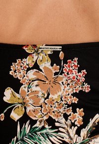 Černá látka s květinovým vzorem v béžové, růžové a zelené barvě; obsahuje štítek "VIVE MARIA". Strukturováno s přiléhavým designem.