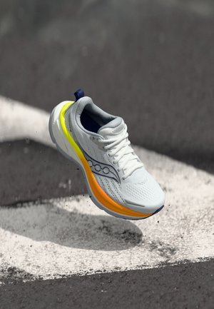 Weißer Laufschuh mit atmungsaktivem Mesh-Obermaterial, gelben und orangefarbenen Akzenten an der Sohle und einer dunkelblauen Fersenschlaufe.