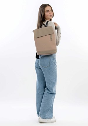 Zaino in morbida pelle color beige con una patta grigia chiara in contrasto. Presenta spallacci regolabili e una maniglia superiore per il trasporto.