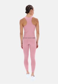 Roza atletska majica bez rukavov in legice, izdelane iz raztegljivega materiala. Majica ima obliko racerback; legice imajo oznako na pasu.