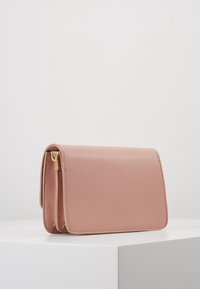 Růžová kožená kabelka s klopou, se zlatým kováním, hladkým povrchem a obdélníkovým tvarem, zdůrazňující čisté linie.