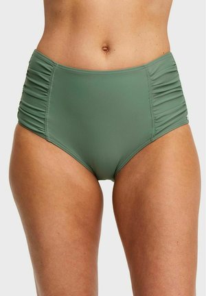 Olijfgroene zwemslip met hoge taille en gerimpelde zijpanelen, gedragen door een persoon met een blote buik en zichtbare benen.