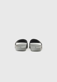 Gray sandals with a smooth texture, open back, and curved design; featuring two thick black straps across the top.