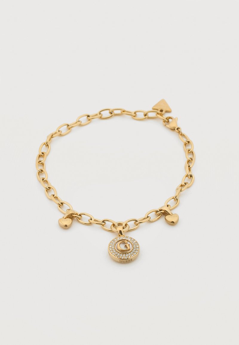 Βραχιόλι από χρυσή αλυσίδα με καρδιές και στρογγυλό μενταγιόν που φιλοξενεί το γράμμα "G", περιτριγυρισμένο από μικρά κρύσταλλα και τη λέξη "Guess".