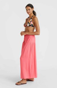 Haut de bikini fleuri avec col halter, associé à une longue jupe maxi corail fluide avec un détail de boutons et une taille froncée. Tongs.