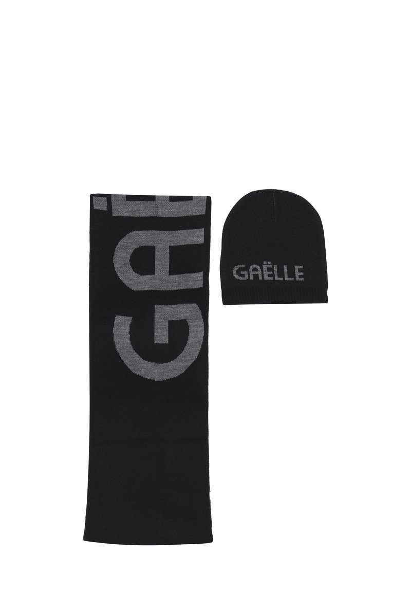 Set di sciarpa e berretto in maglia nera con grande testo grigio "GAËLLE" sulla sciarpa e testo più piccolo sul berretto.