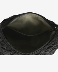 Schwarze gepolsterte Tasche mit offenem Reißverschluss, die das leere beige Innentuch und ein kleines Etikett darin zeigt.
