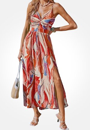 Maxi-jurk van lichtgewicht stof, met rode en blauwe abstracte patronen, een split aan de voorkant en verstelbare spaghetti bandjes. Aangevuld met een witte tas.