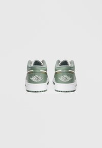 Nízkoprofilové tenisky zo zelenej a bielej kože. Obsahujú sieťovaný jazyk, dve bočné pruhy a výrazné biele logo na päte. Textúrovaná gumová podrážka.