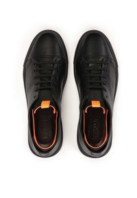 Black leather sneakers with a rounded toe, black laces, and an orange interior accent. Features a textured tongue and logo detail on the side.