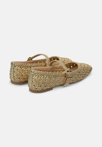 Zapatos planos de hilo dorado con punta afilada, correa decorativa y acentos metálicos. Forro interior suave y suela plana. Superficie texturizada.