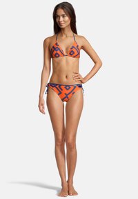 Ensemble de bikini comprenant un haut triangulaire et un bas à nouer sur le côté, fabriqué en tissu orange avec un motif géométrique bleu et une texture lisse.