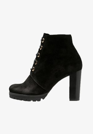 Botte de cheville en daim noir avec un bout arrondi, un devant lacé, des œillets dorés et un talon large. Semelle texturée pour une adhérence optimale.