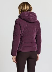 Giacca imbottita in viola scuro con design trapuntato orizzontale, dotata di cappuccio e maniche aderenti. Tessuto liscio e lucido con una texture soffice.