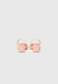 Pink high-heeled sandals with a woven texture, square heels, and ankle straps. Smooth leather-like material and outlined edges.
