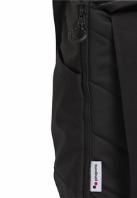 Schwarzer Stoff-Rucksack mit einem Reißverschlussfach, gestepptem Muster und einem Markenlabel mit bunten Punkten. Kompaktes Design und strapazierfähiges Material.