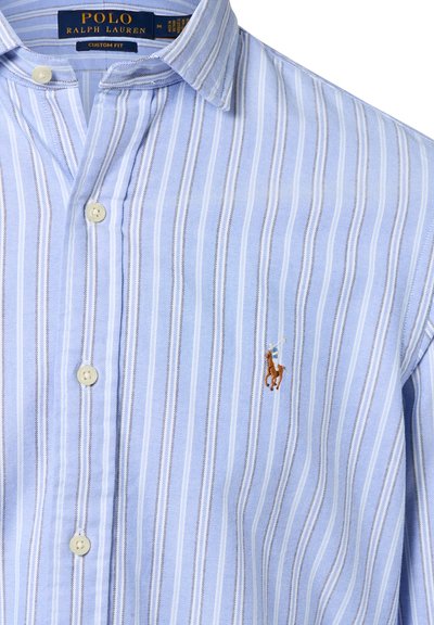 Blauw-wit gestreepte korte mouwen shirt met een button-down kraag; heeft een klein bruin en gouden geborduurd polo speler logo op de borst.