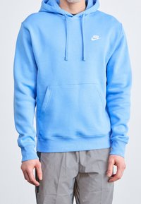 Světlé modrá mikina Nike z měkké látky, s přední kapsou, kapucí na stažení a malým bílým logem na hrudi.