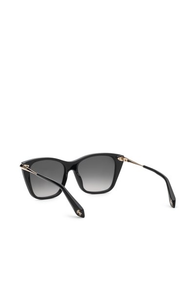 Lunettes de soleil noires œil-de-chat avec verres sombres dégradés et accents dorés sur les charnières et les extrémités des branches, montrées inclinées sur une surface blanche.