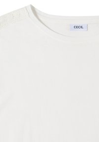 T-shirt blanc à col rond avec un détail en dentelle sur l'épaule et une étiquette de marque indiquant "CECIL" à l'intérieur du col.