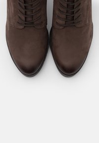 Braune Lederschuhe mit einer glatten Textur, runder Zehenform und Schnürsystem; verfügen über robuste Nähte und eine flache Sohle.