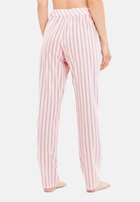 Lösa, pastellrosa pyjamasbyxor med vertikala ränder i marinblått. Har en elastisk midja och är tillverkade av lätt, mjukt tyg.