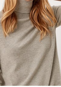 Pull à col roulé gris clair fabriqué à partir d'un tissu doux et texturé. Présente une coupe ajustée avec un col montant et des manches amples et fluides.