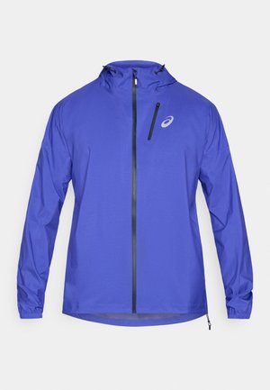 Lila leichte Jacke mit Reißverschluss vorne, verstellbarer Kapuze und elastischen Bündchen. Verfügt über eine kleine Reißverschlusstasche und ein Logo auf der Brust.