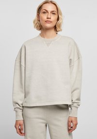 Lys grå, oversized genser med rund hals, ribbede mansjetter og V-søm detalj ved kragen, laget av mykt stoff.