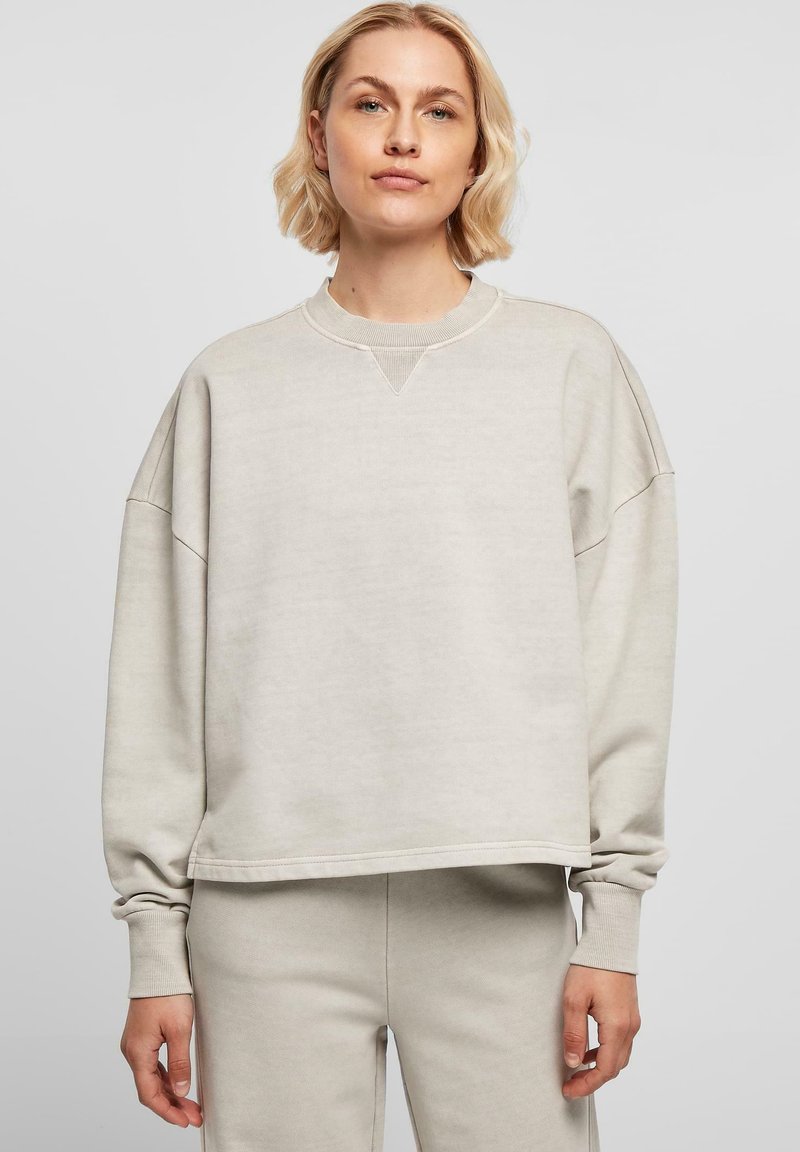 Lys grå, oversized genser med rund hals, ribbede mansjetter og V-søm detalj ved kragen, laget av mykt stoff.