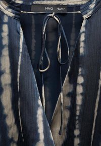 Robe tie-dye bleu marine et beige avec décolleté en V profond, fines longues cordons noués au col, et étiquette de la marque MNG indiquant la taille EUR S USA 4 MEX CH.