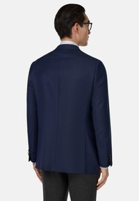 Námornícky blejzer so štruktúrovanými ramenami, jedným rozparkom a hladkou látkou. Obsahuje kontrastné manžety a elegantné gombíky pre rafinovaný detail.