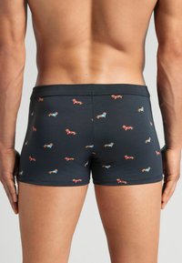 Boxer briefs elásticos en navy oscuro con un estampado juguetón de dachshund en rojo y azul. Textura suave, diseño ajustado, corte de baja cintura.
