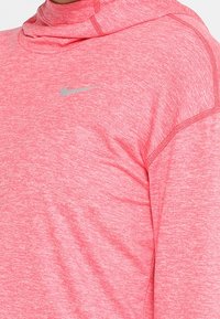 Felpa con cappuccio rosa mélange caratterizzata da un collo alto, maniche lunghe e un piccolo logo Nike in argento sul petto, realizzata in un morbido tessuto texturizzato.