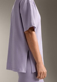 T-shirt corto viola lavanda con vestibilità rilassata, maniche corte, spacchi laterali e una texture liscia. Cuciture rinforzate per una maggiore durata.