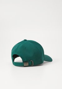 Casquette de baseball en coton verte avec une visière incurvée, bandeau réglable à l'arrière et un bouton rond en haut. Présente une plaque de logo métallique.
