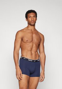 Marineblaue Boxershorts mit einem schwarzen Nike-Bund, die eine enganliegende Passform und eine glatte Textur bieten. Das Design hat eine nahtlose Vorderseite und seitliche Abdeckung.