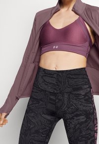 Sporty outfit featuring a purple sports bra and high-waisted black leggings with a textured pattern, complemented by a matching zip-up jacket.