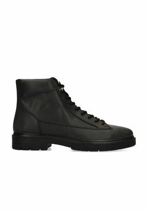 Bottine noire en cuir avec lacets et œillets métalliques, semelle épaisse en caoutchouc et bout arrondi.