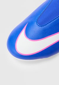 Μπλε συνθετικό ποδοσφαιρικό παπούτσι με υφή, που διαθέτει μια εμφανή λευκή χαρακτηριστική μάρκα Nike περιγραμματισμένη σε ροζ. Λείας σόλας για καλύτερη πρόσφυση.