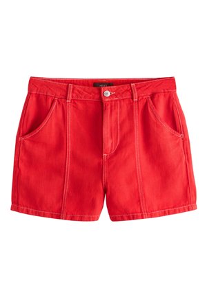 Shorts in denim rossi con tasche anteriori, passanti per cintura, cuciture bianche, chiusura con bottone e etichetta del marchio visibile all’interno della vita.