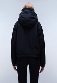 Giacca nera con cappuccio dal design aderente, realizzata in un materiale liscio e resistente all'acqua. Presenta un colletto alto e polsini elastici.