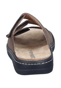 Braune Ledersandale mit zwei verstellbaren Riemen, weichem beigem Fußbett, schwarzer Gummisohle und kontrastierenden weißen Steppnähten.