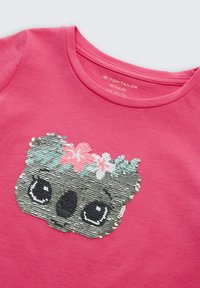 Chemise rose pour enfants avec un visage de koala en sequins portant une couronne de fleurs dans des teintes de rose, blanc et vert menthe sur le devant.